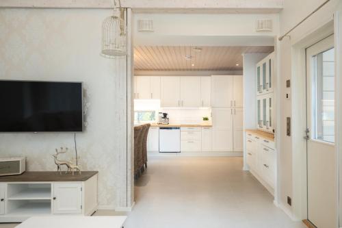 a kitchen with white cabinets and a tv on the wall at Luxurious Villa Kinos with Jacuzzi in Rovaniemi