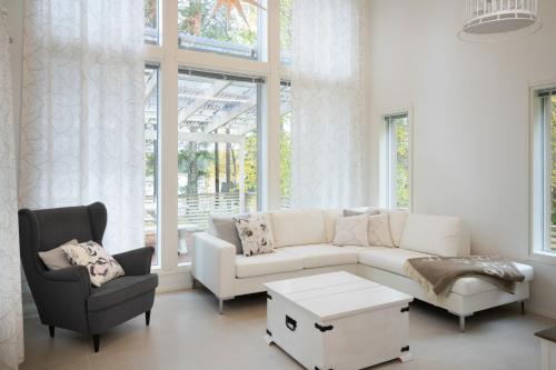 a living room with a white couch and a chair at Luxurious Villa Kinos with Jacuzzi in Rovaniemi