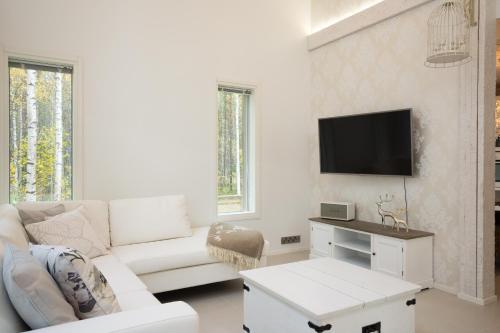 a white living room with a white couch and a tv at Luxurious Villa Kinos with Jacuzzi in Rovaniemi