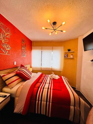 a bedroom with a bed with a red wall at Habitación Deluxe in Orizaba