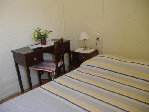 a bedroom with a bed and a desk and a table with a lamp at Residência Ideal in Coimbra