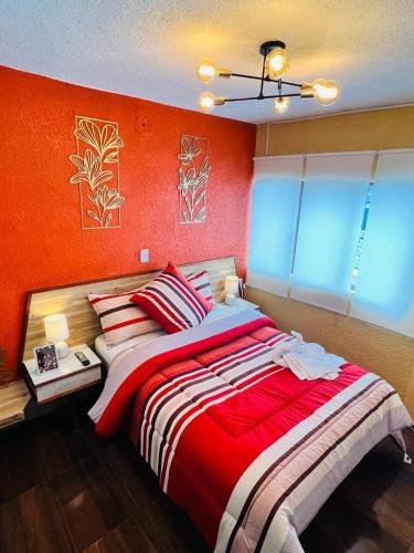 a bedroom with a large bed with an orange wall at Habitación Deluxe in Orizaba