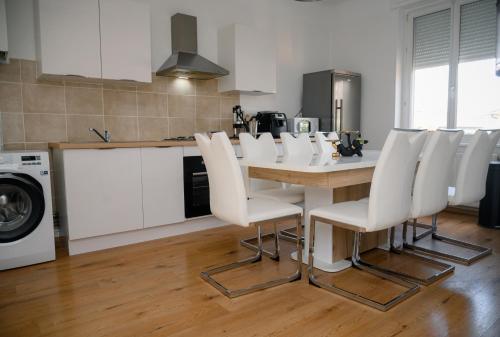 - une cuisine avec une table en bois et des chaises blanches dans l'établissement Christophe, à Yutz