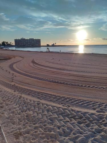 a beach with tracks in the sand at sunset at Palacio del mar in Torrevieja