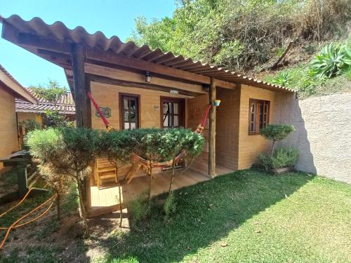 een klein huis met een veranda en een tuin bij Chalés do Alcantilado in Santo Antônio do Pinhal