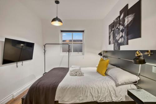 een slaapkamer met een bed met gele kussens en een televisie bij Apartment in Shoreditch/ Old St in Londen