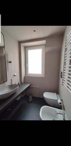 a bathroom with a toilet and a sink and a window at La Martina Home in Valguarnera Caropepe