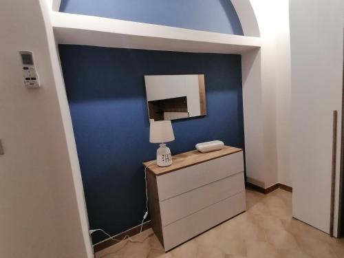 a room with a blue wall and a lamp on a dresser at Casa dell’Assunta in Trani