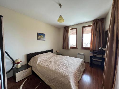 a bedroom with a bed and a desk and two windows at Regnum Bansko in Bansko
