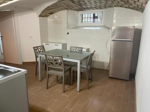 una cucina con tavolo, sedie e frigorifero di DOLCEVITA PONTE MILVIO a Roma