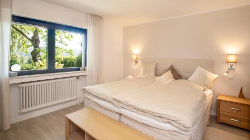a white bedroom with a large bed and a window at Biloba Garden in Wengern