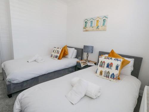 two beds in a room with white sheets and pillows at The Willows in Weymouth