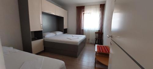 a small bedroom with two beds and a window at Apartman ll smještaj između Splita i Trogira su Kaštela Dalmacija Hrvatska in Kaštela
