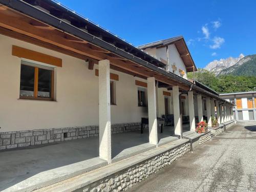 a house with a porch with mountains in the background at Lunga Via Delle Dolomiti in Calalzo