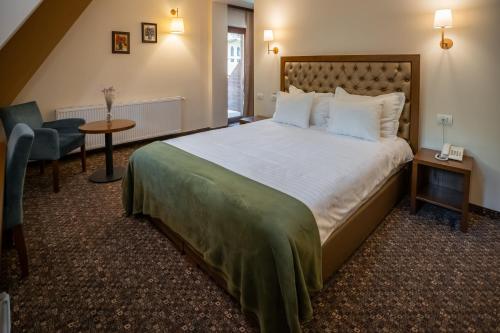 a hotel room with a large bed and a chair at Opus Villa in Sinaia