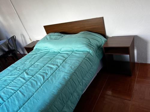 a bed with a green comforter and a wooden table at Apto AMARILLO in Rocha
