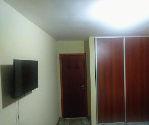 Habitación con TV y puerta de madera. en Departamento 5 en Puerto Iguazú