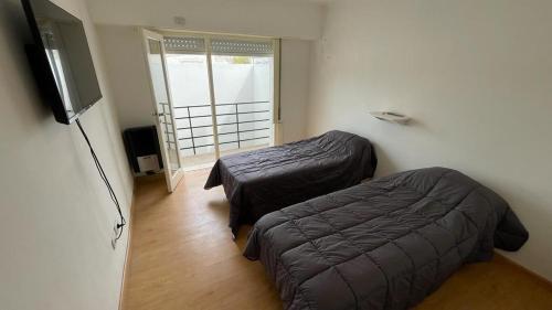 1 Schlafzimmer mit 2 Betten und einem Flachbild-TV in der Unterkunft Departamentos San Lorenzo in Tres Arroyos