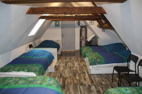Cette chambre mansardée comprend 3 lits et une table. dans l'établissement Location maison Bourboule, à Murat-le-Quaire