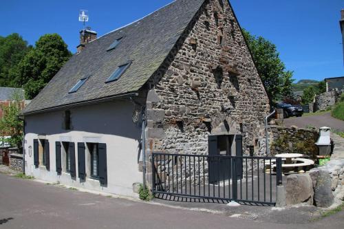 an old stone building with a black fence around it at Location maison Bourboule in Murat-le-Quaire
