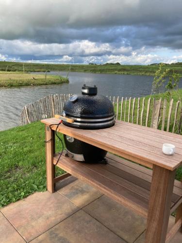a grill sitting on a picnic table next to a lake at Tiny vakantiehuis aan het water met eigen steiger en airco in Kampen