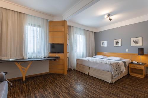 a hotel room with a bed and a desk at Green Place Ibirapuera in São Paulo