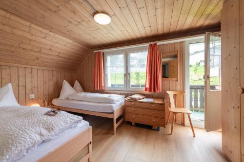 a bedroom with a bed and a desk and a window at Schwendi Lodge in Unterwasser
