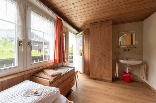 a bedroom with a bed and a sink and windows at Schwendi Lodge in Unterwasser