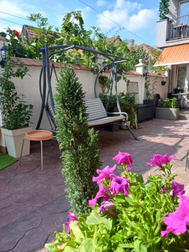 a swing in a garden with pink flowers at Kuća za odmor sa 3 spavaće sobe in Kragujevac