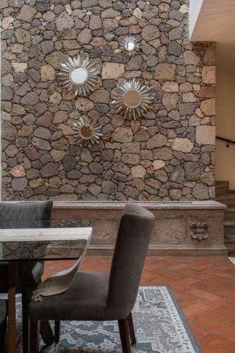 a room with a stone wall with a table and chairs at Casa del Palmar, Elegant 3BR Home with Rooftop in Centro San Miguel in San Miguel de Allende