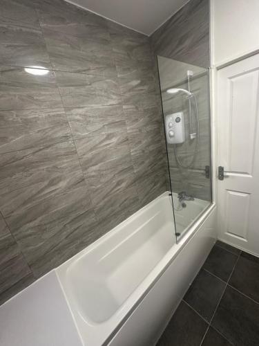 Sutton Coldfield Apartment في برمنغهام: حمام مع حوض استحمام أبيض ودش