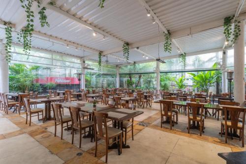 a restaurant with tables and chairs in a room with windows at Green Place Ibirapuera in Sao Paulo