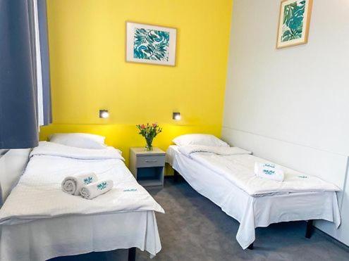 two beds in a room with a yellow wall at Hotel Jabłoński in Dorotowo