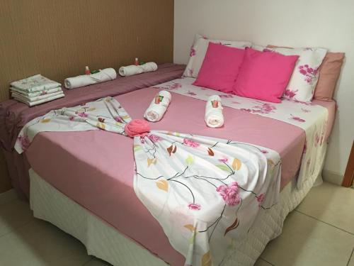 a bed with pink and white sheets and pink pillows at Apartamento a beira mar com piscina estilo resort in Cabedelo