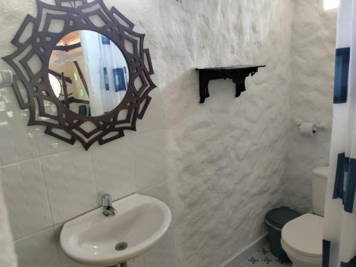 een badkamer met een wastafel, een spiegel en een toilet bij Payande - Tatacoa in Villavieja
