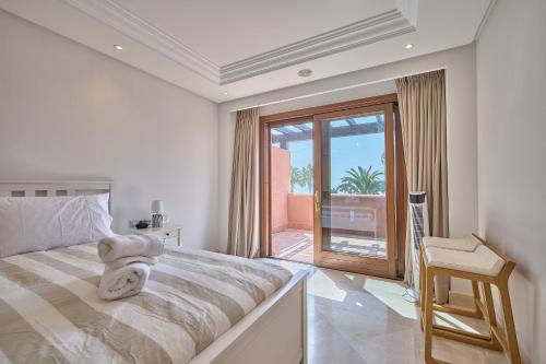 a white bedroom with a bed and a balcony at Mar Azul by La Maison Marbella Rentals in Estepona