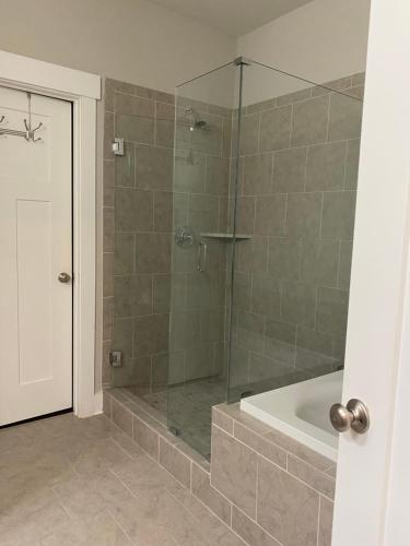 a bathroom with a shower with a bath tub at The Haven at Estuary in Huntsville