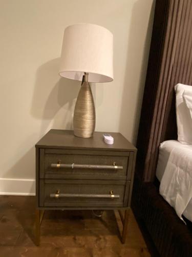 a lamp on a night stand next to a bed at The Haven at Estuary in Huntsville