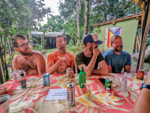 Un groupe d'hommes assis autour d'une table dans l'établissement Kehena Mauka Nui Club LGBTQIA+ Clothing Optional, à Pahoa