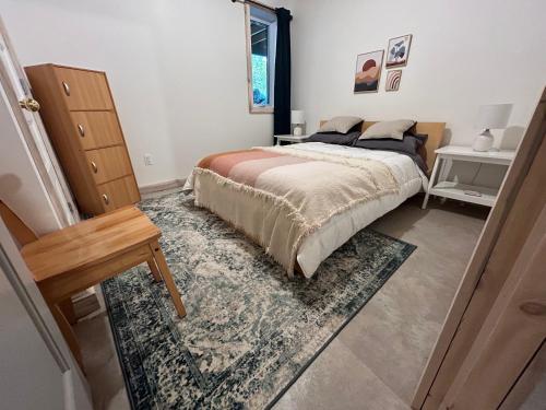 a bedroom with a bed and a rug at le vénÉrable in LʼAnse-Saint-Jean