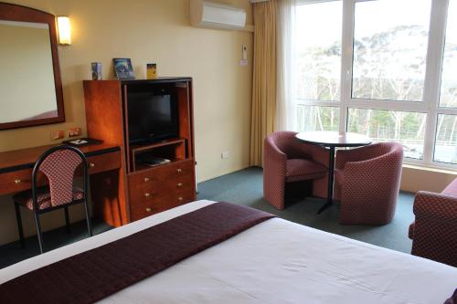 a hotel room with a bed and a flat screen tv at Alpine Motor Inn in Katoomba