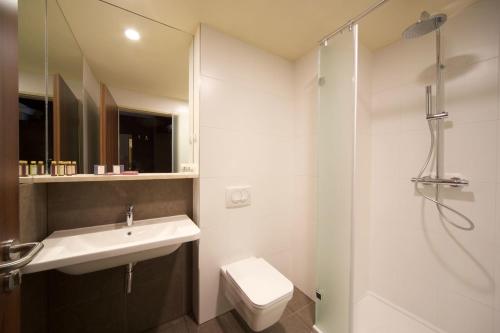 a bathroom with a toilet, sink, and shower at 12 Revay Hotel in Budapest