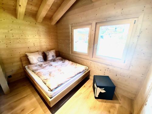 a bed in a wooden room with a window at Chalet Neuf, Morgins in Morgins