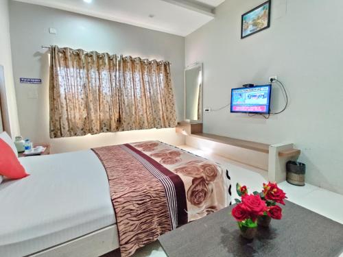 a bedroom with two beds and a tv on the wall at HOTEL NIMBA INTERNATIONAL in Rānībennur