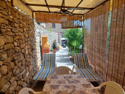 een patio met een tafel en stoelen en een stenen muur bij Cilento Paradise - Appartamento con terrazzo in Marina di Pisciotta in Pisciotta