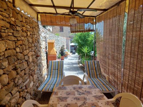 a patio with a table and chairs and a stone wall at Cilento Paradise - Appartamento con terrazzo in Marina di Pisciotta in Pisciotta