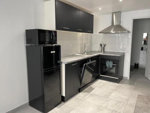 eine Küche mit schwarzen Schränken und einem schwarzen Kühlschrank in der Unterkunft Résidence du Temple in Martigues