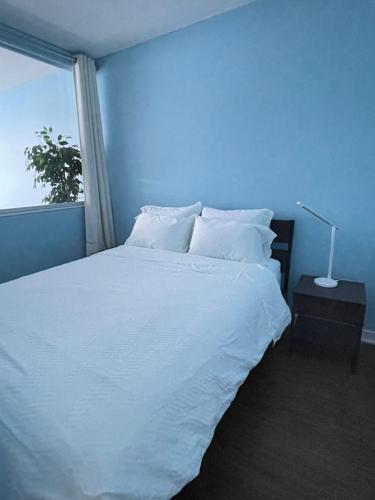 Dormitorio azul con cama blanca y ventana en Downtown 1BR Condo at Granville Strip near English Bay, en Vancouver