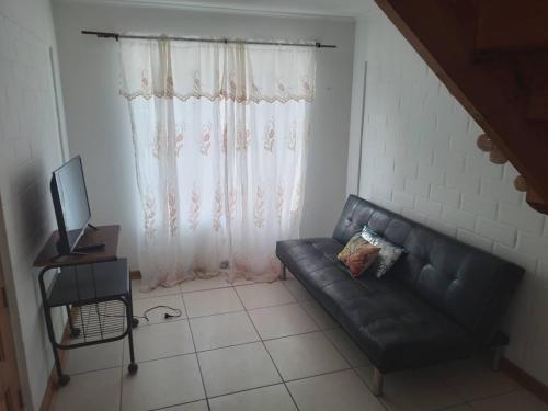 sala de estar con sofá de cuero negro frente a una ventana en Casa condominio, en Coquimbo