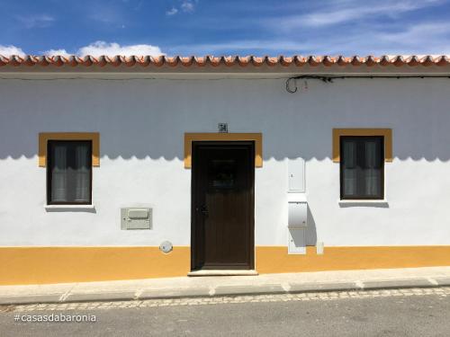 a white building with a black door and three windows at casas da Baronia casa Catarina in Vila Nova da Baronia